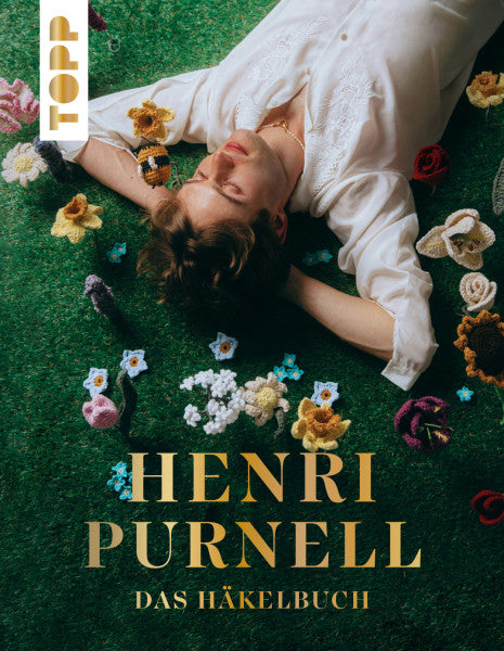 Titelbild Henri Purnell Das Häkelbuch zeigt Henri Purnell liegend auf einer Häkeblumenwiese, Topp Verlag