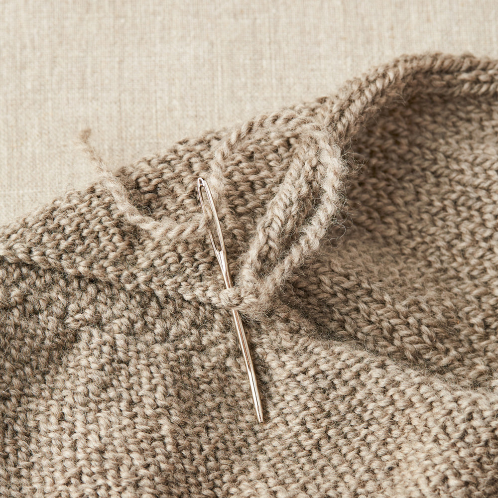 Cocoknits Tapestry Needle, Nadelset zum Vernähen von Strickstücken, hier in Aktion, steckt in einer Naht mit eingefädeltem Faden
